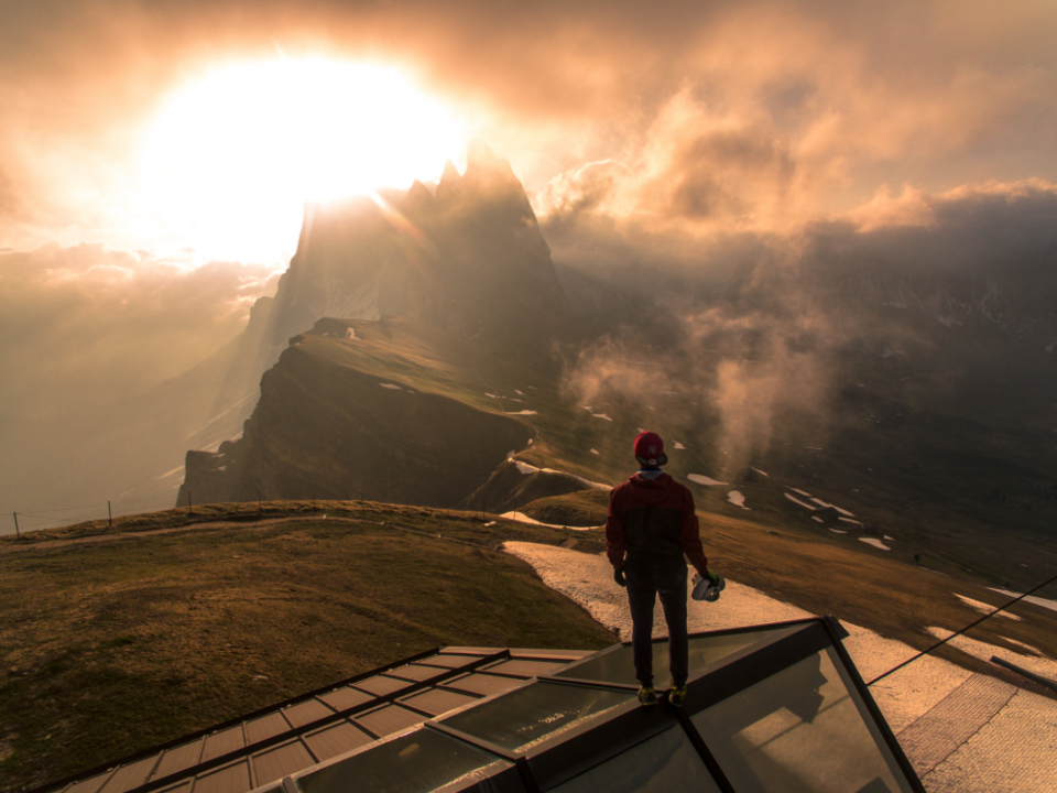 En person står alene på en fjelltopp i solnedgang