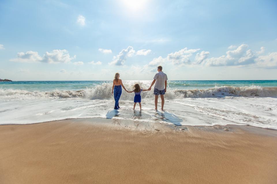 Familie som går hånd i hånd i strandkanten